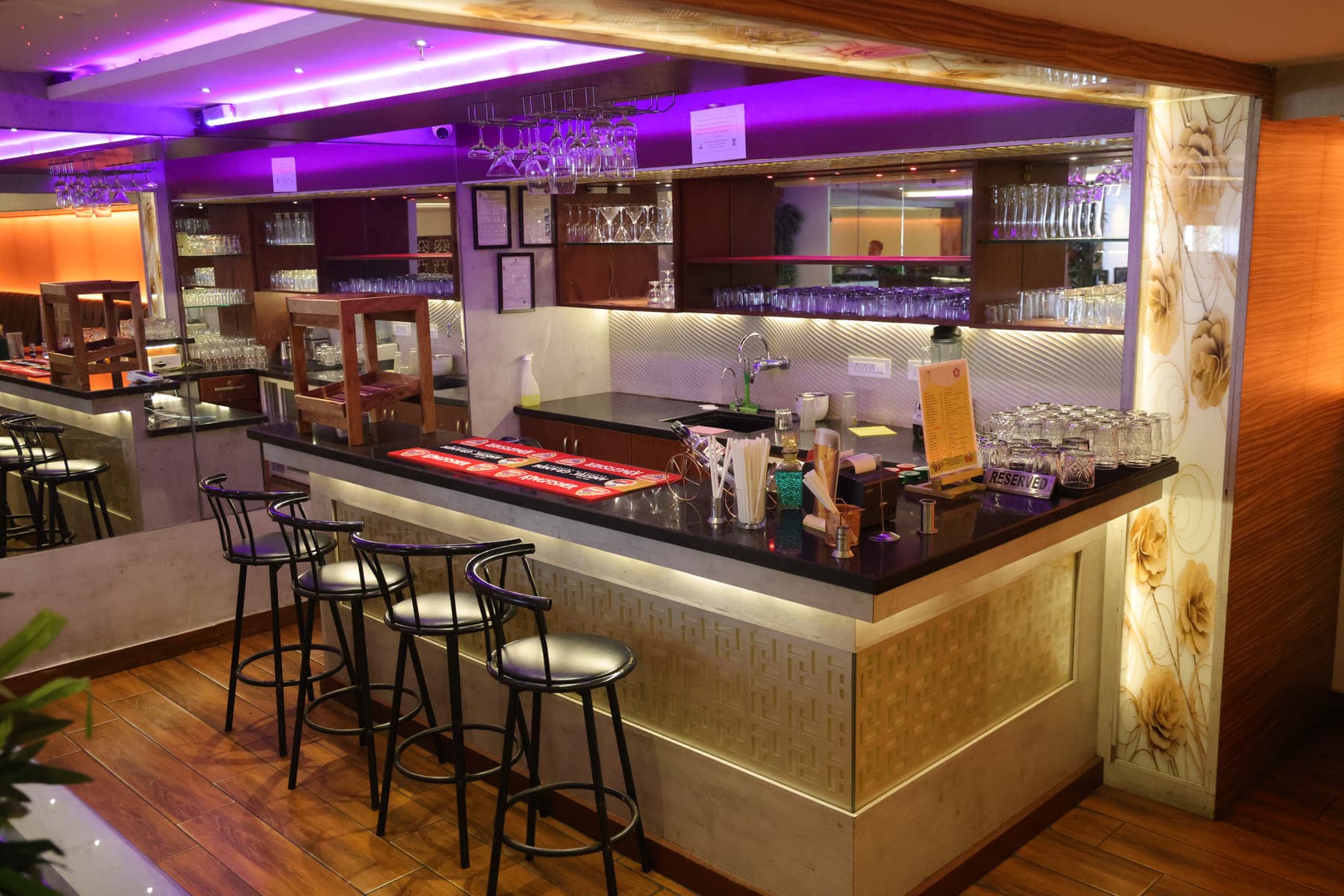 The bar counter with high stools and glassware on the shelves behind