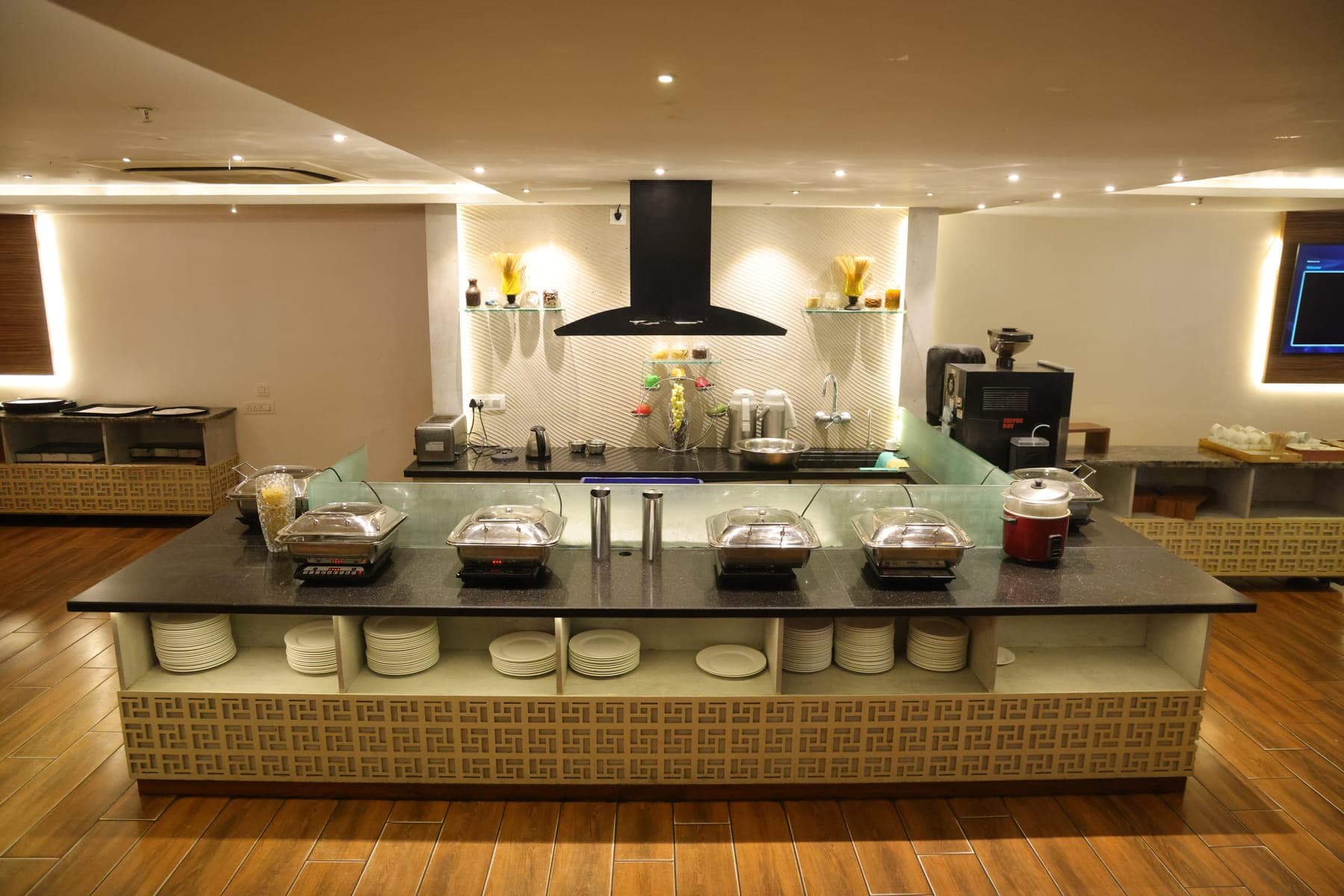 The buffet counter set for breakfast, with chafing dishes and stacked plates