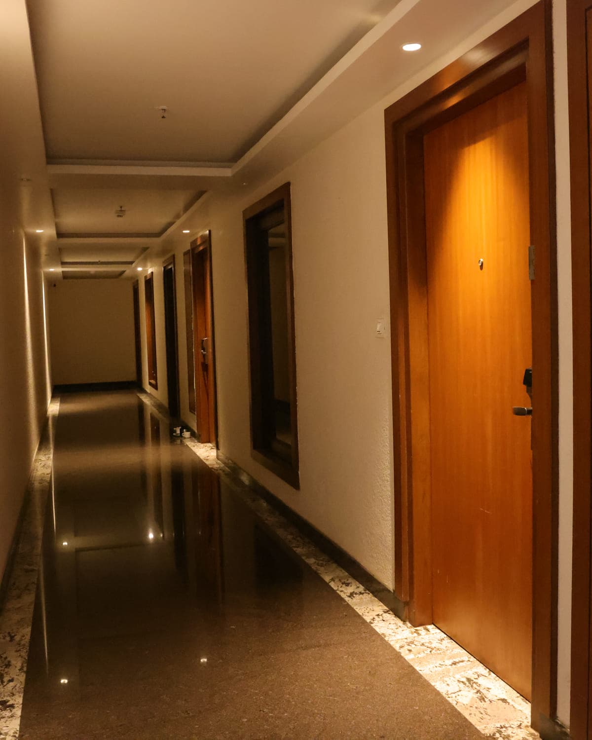 A guest-room corridor, with polished floors and warm lighting