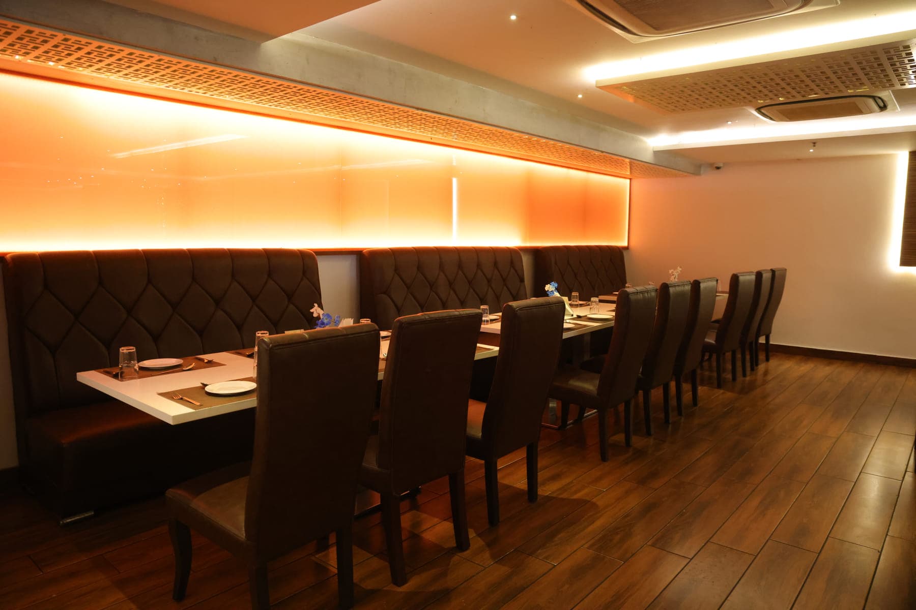 A long table laid for a private party, lit by warm wall lighting