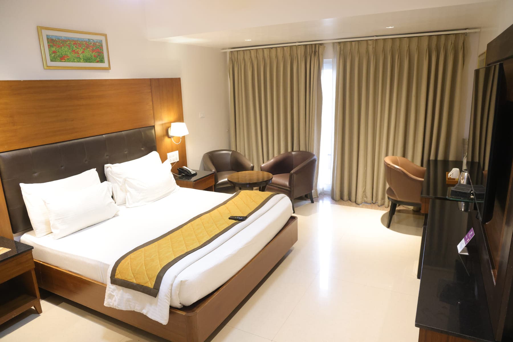 The bedroom of a Suite Room, with a king-size bed and a window overlooking the street