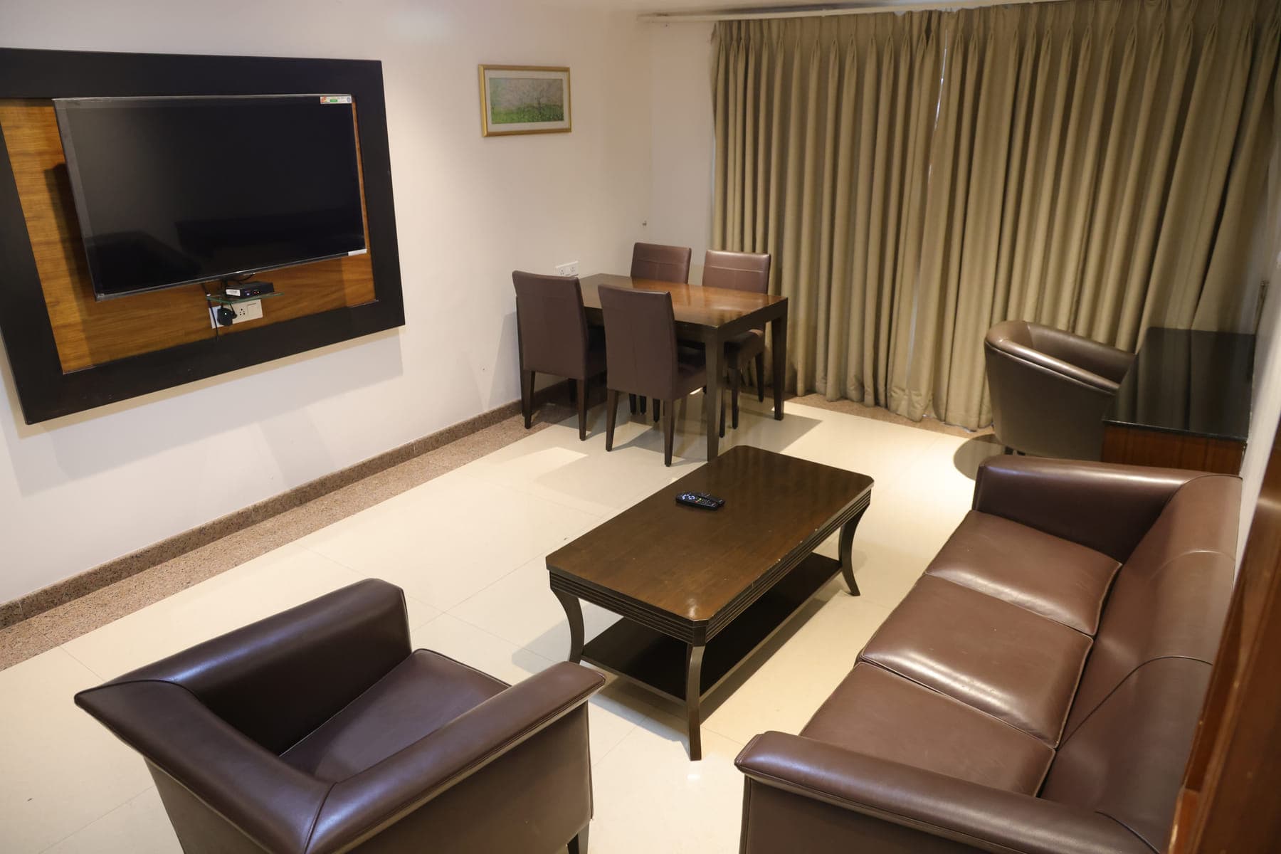 The separate living room of a Suite Room, with leather sofas, a coffee table and a dining table