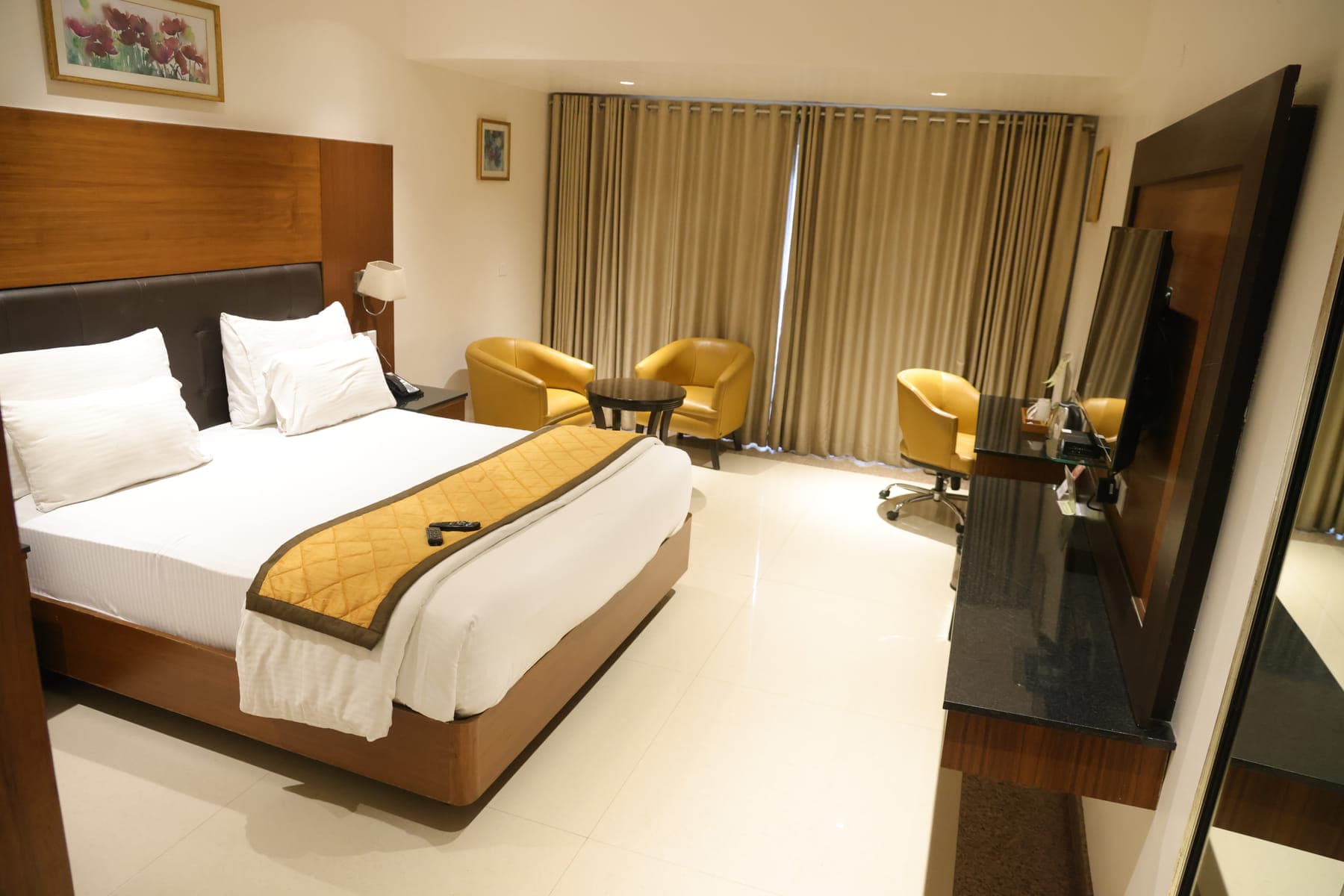 A Superior AC Room, with floor-to-ceiling curtains and a seating area beside the window