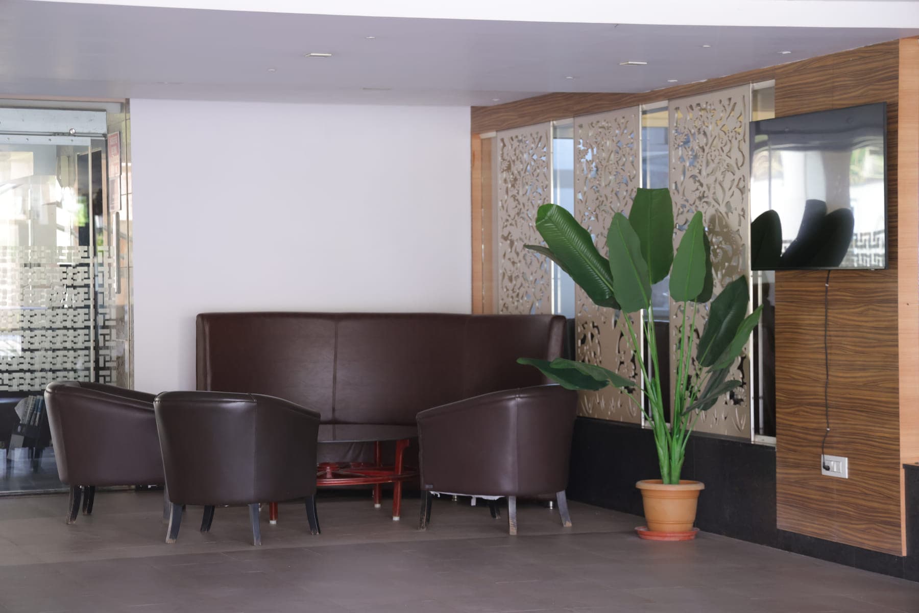 The waiting area, with tub chairs and a banquette beside a potted plant